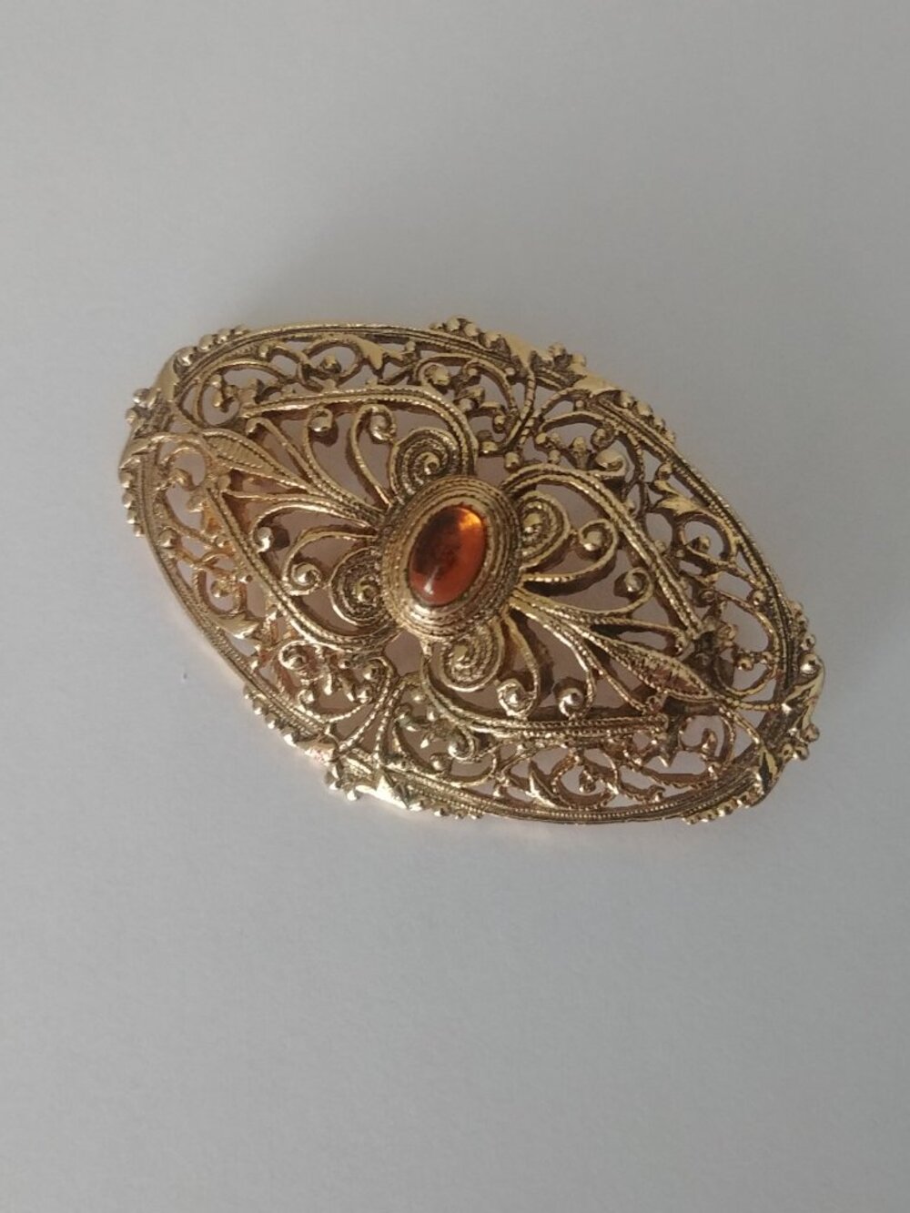 Vintage intricate gold tone brooch pin with amber look centre stone